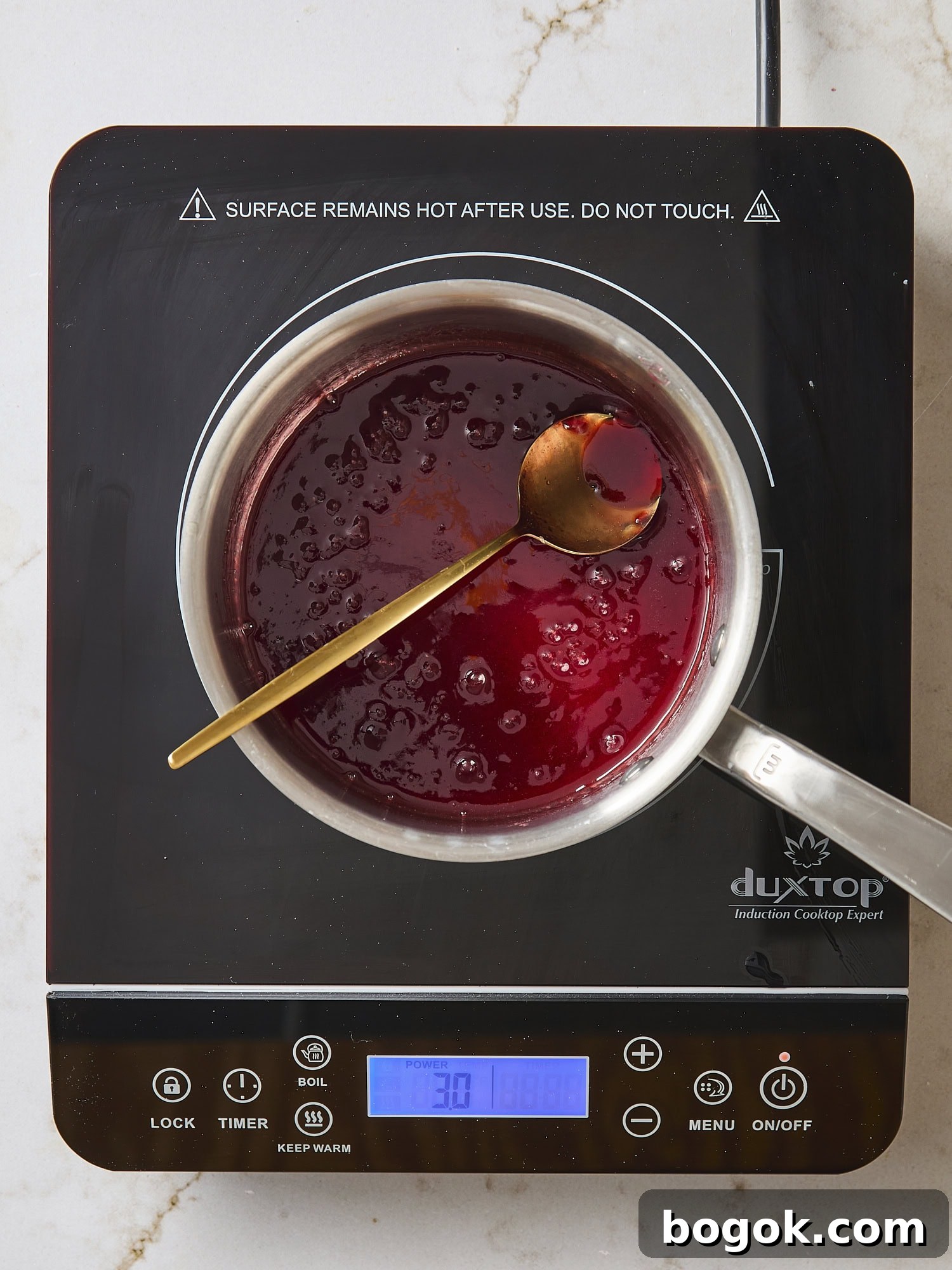 Simple raspberry jam glaze heating in saucepan.