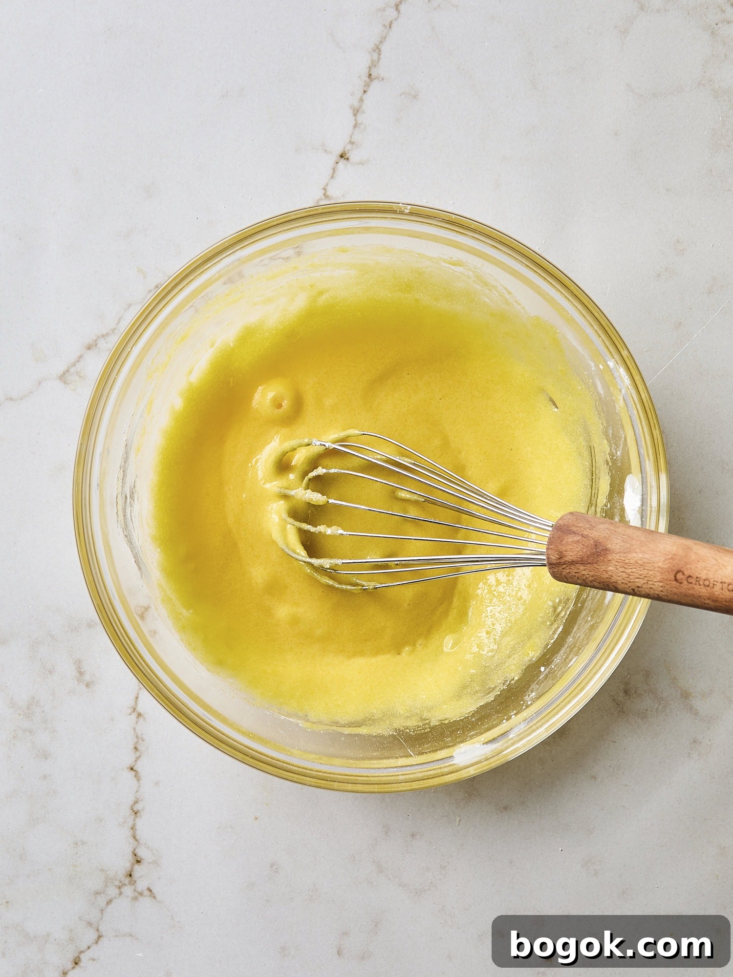 Whisked egg yolks in a glass bowl.