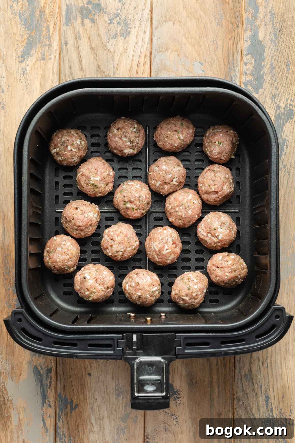 Crispy Air Fryer Turkey Meatballs with Garlic Herb Sauce 5 Uncooked meatballs in an air fryer basket.