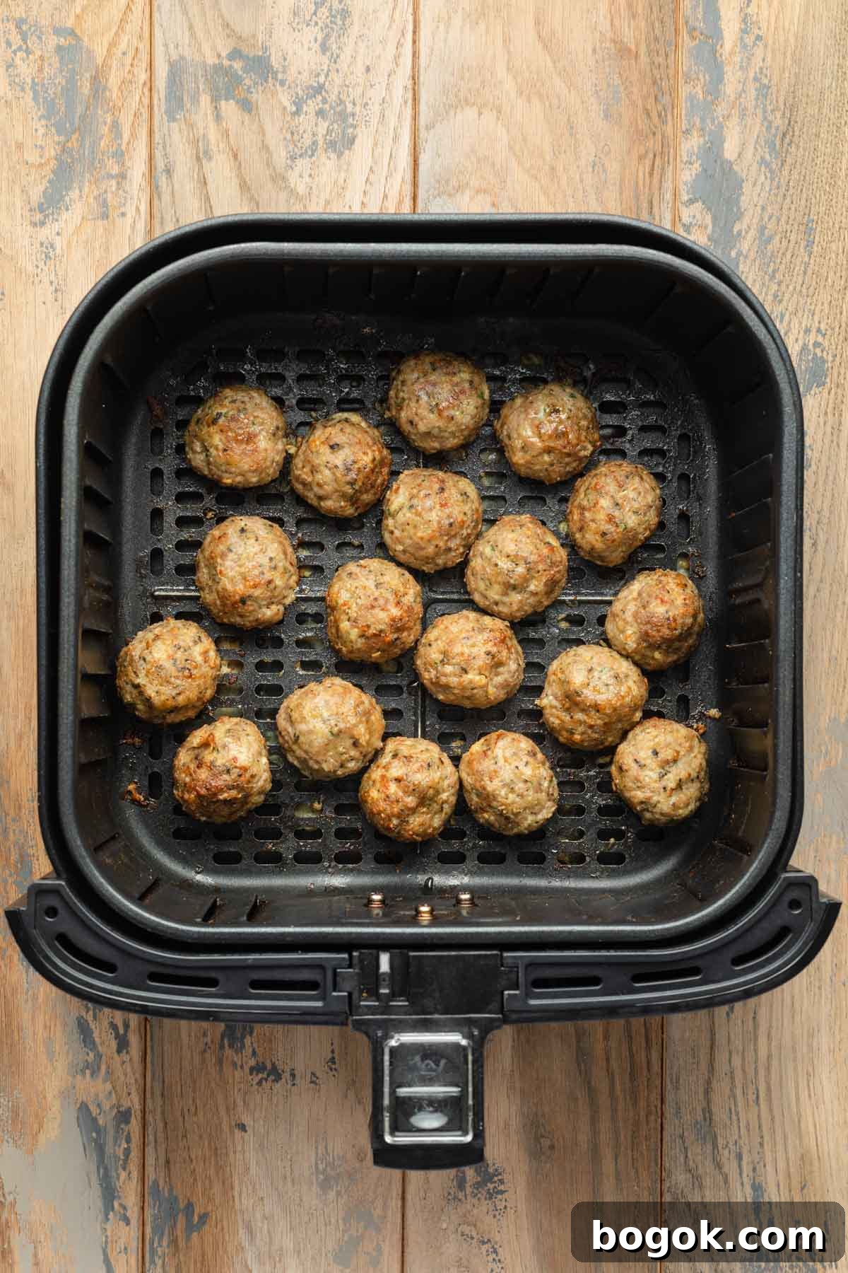 Crispy Air Fryer Turkey Meatballs with Garlic Herb Sauce 6 Cooked turkey meatballs in an air fryer basket.