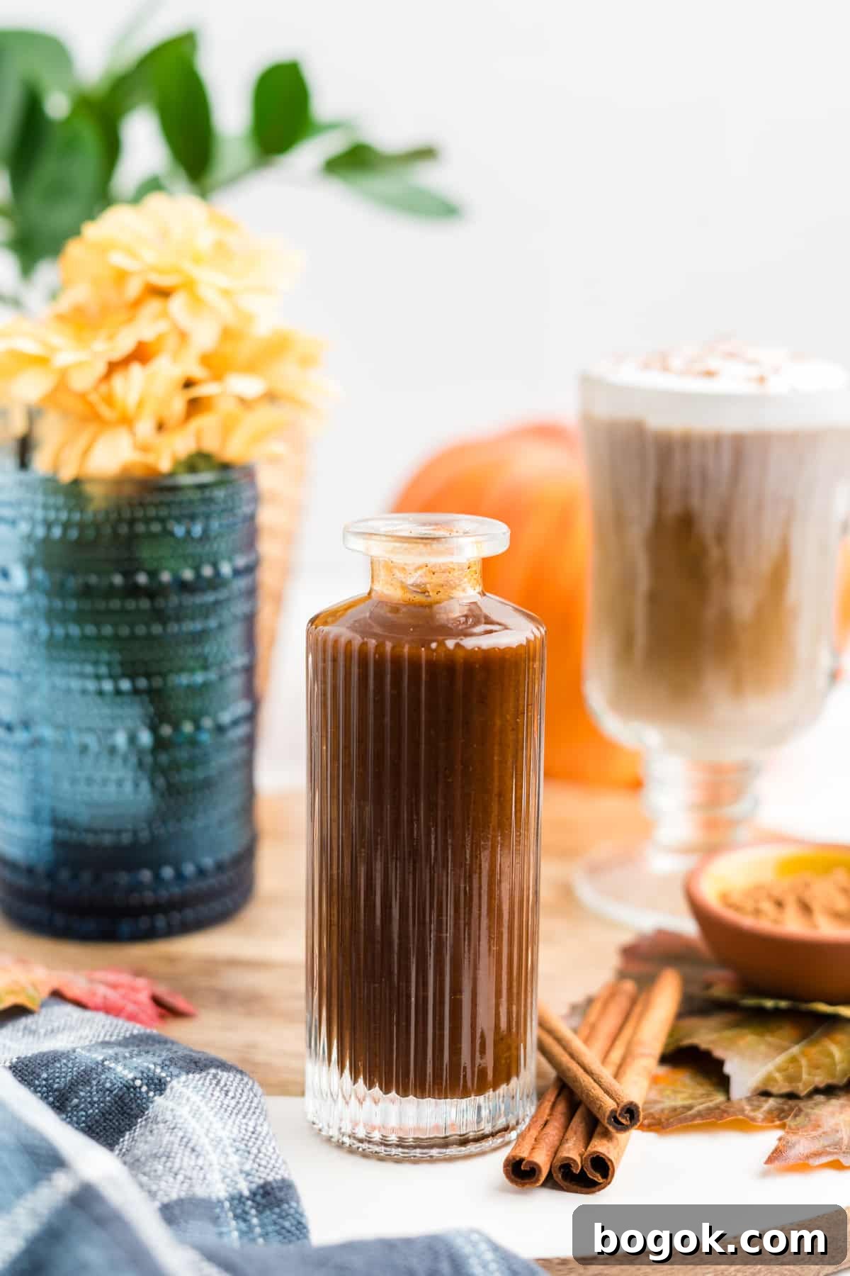 Homemade Pumpkin Spice Syrup in a syrup bottle with fall decor surrounding it.