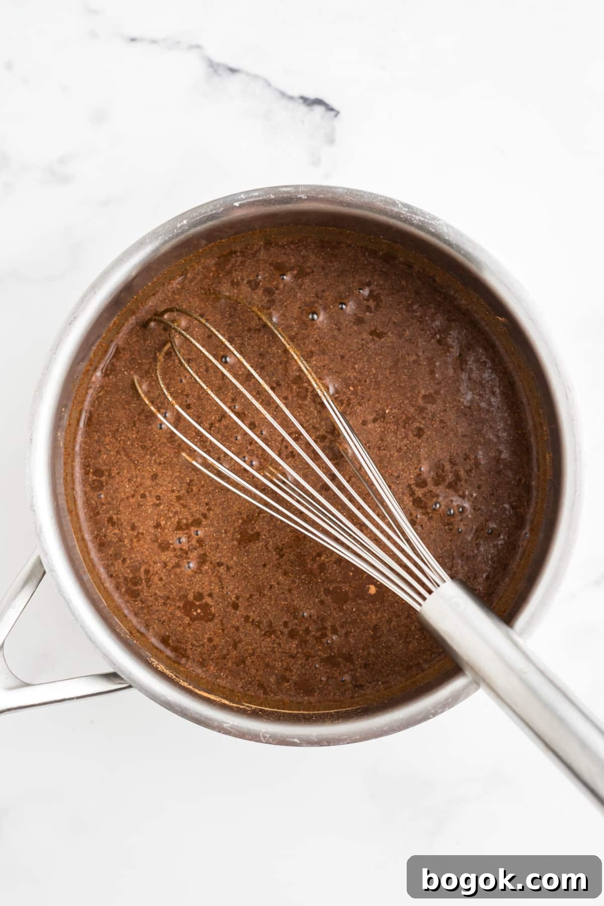Ingredients for syrup being whisked in a saucepan.