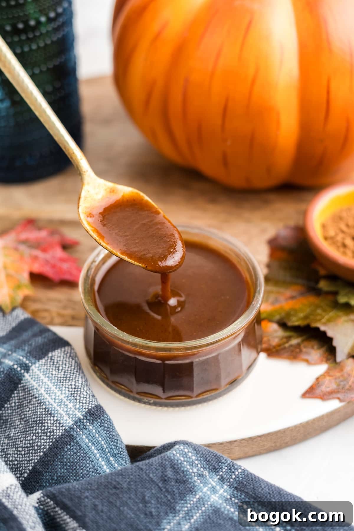 Pumpkin Spice Syrup in a jar being drizzled with a spoon.