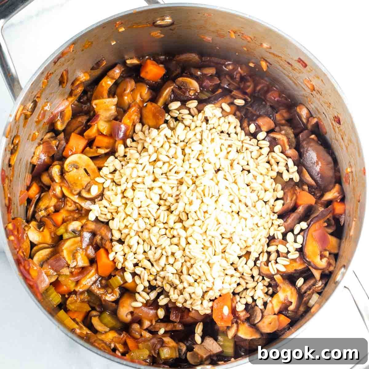 Hearty Vegan Miso Mushroom and Barley Soup Recipe 12 Dried pearl barley on top of sauteed veggies in tomato sauce in a soup pot.