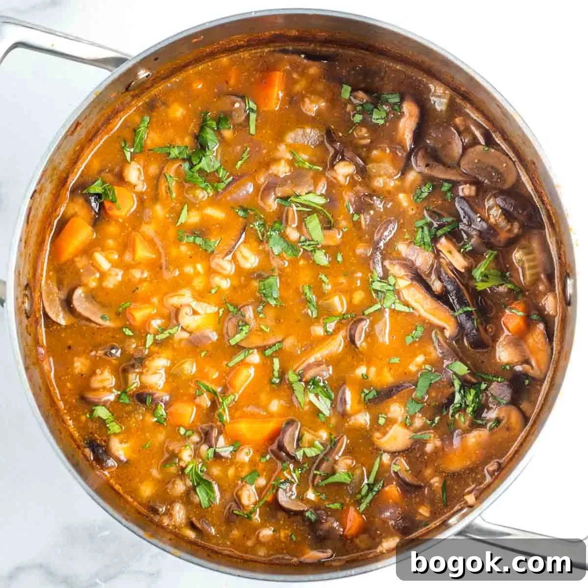 Hearty Vegan Miso Mushroom and Barley Soup Recipe 15 Mushroom barley soup in a tomato broth, with chunks of carrots, sprinkled with fresh herbs.