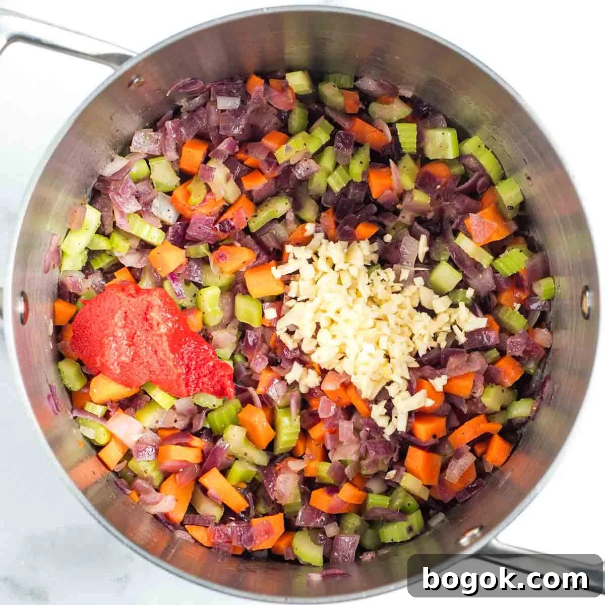 Hearty Vegan Miso Mushroom and Barley Soup Recipe 8 Sauteed carrot, onion and celery in a soup pot with tomato paste and garlic added on top.