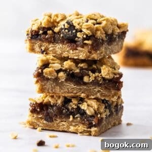 Fruit Mince Oatmeal Bars Recipe — Chewy Fruit & Oat Squares 13 Stack of three pieces of Fruit Mince Oatmeal Bars sitting on a marble benchtop.