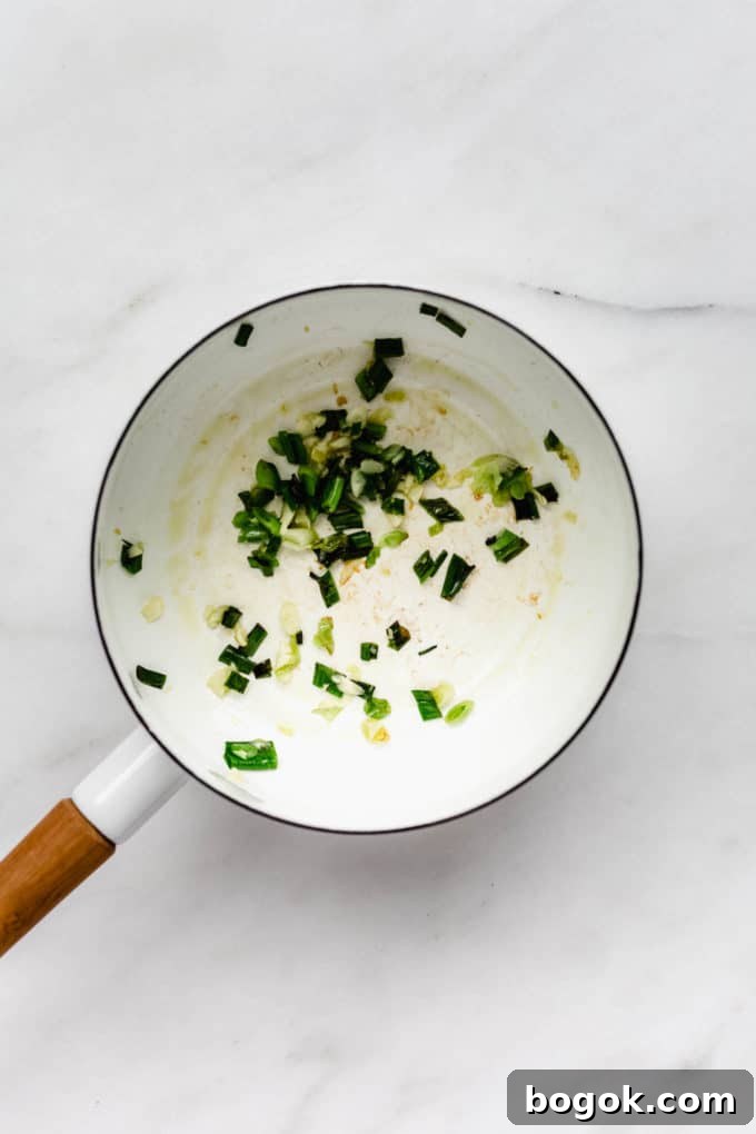 Creamy Peanut Butter Noodles Recipe with Garlic and Soy 4 A white pot with sautéed green onions in it