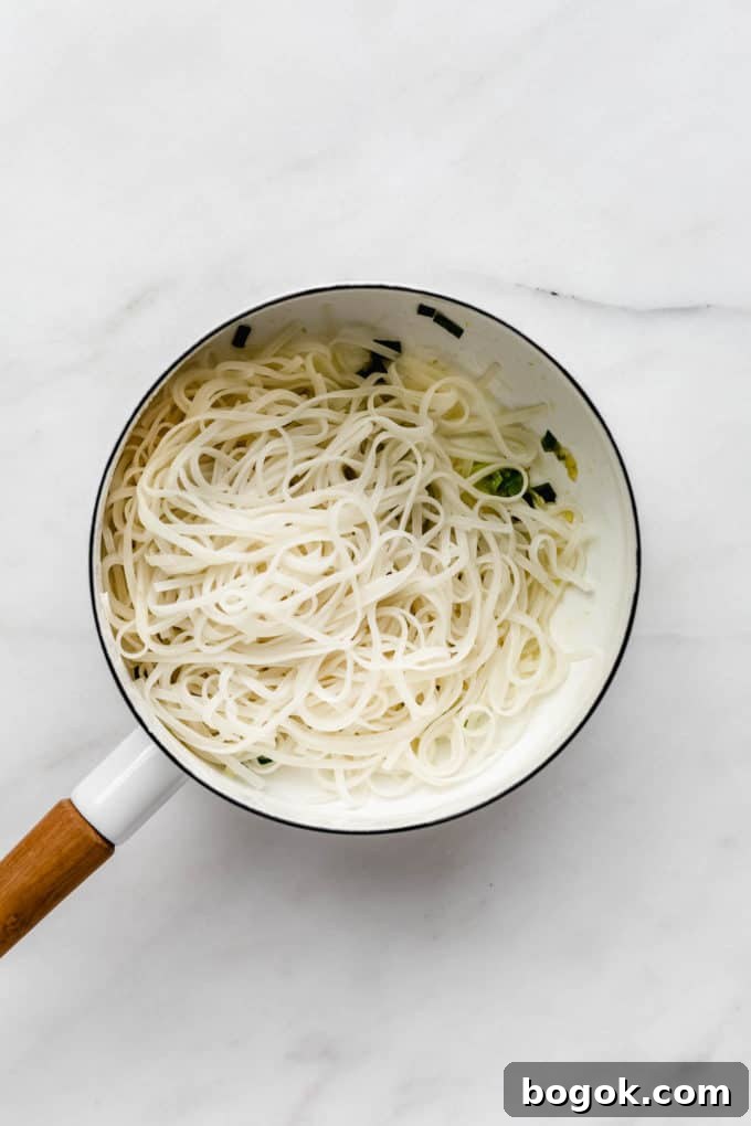 Creamy Peanut Butter Noodles Recipe with Garlic and Soy 5 A white pot with rice noodles in it