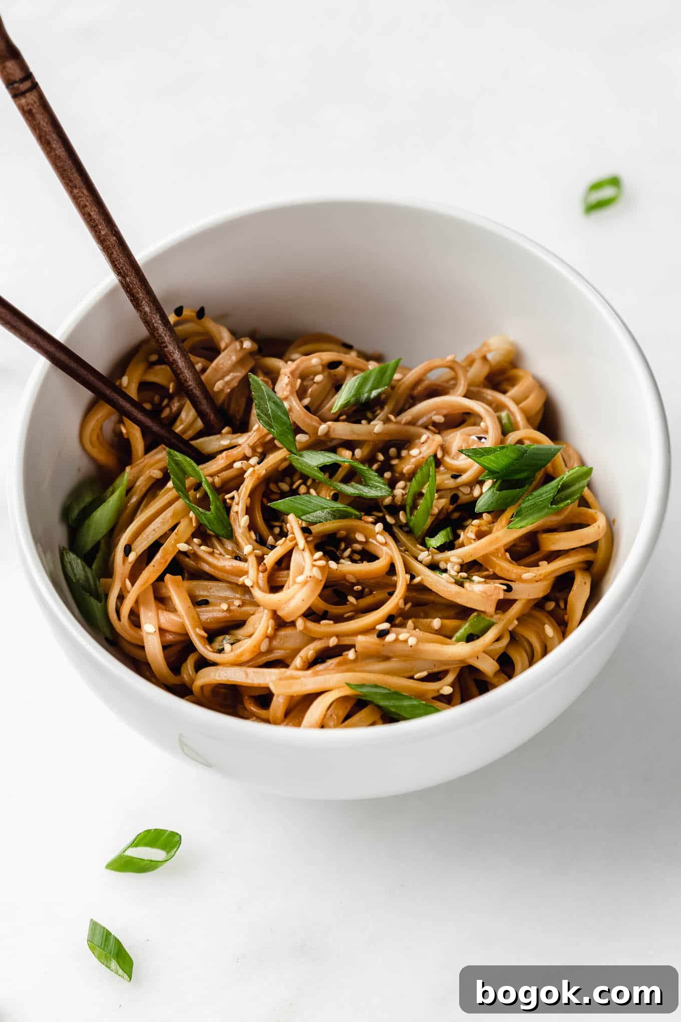 Creamy Peanut Butter Noodles Recipe with Garlic and Soy 8 Peanut butter noodles in a white bowl topped with green onions.