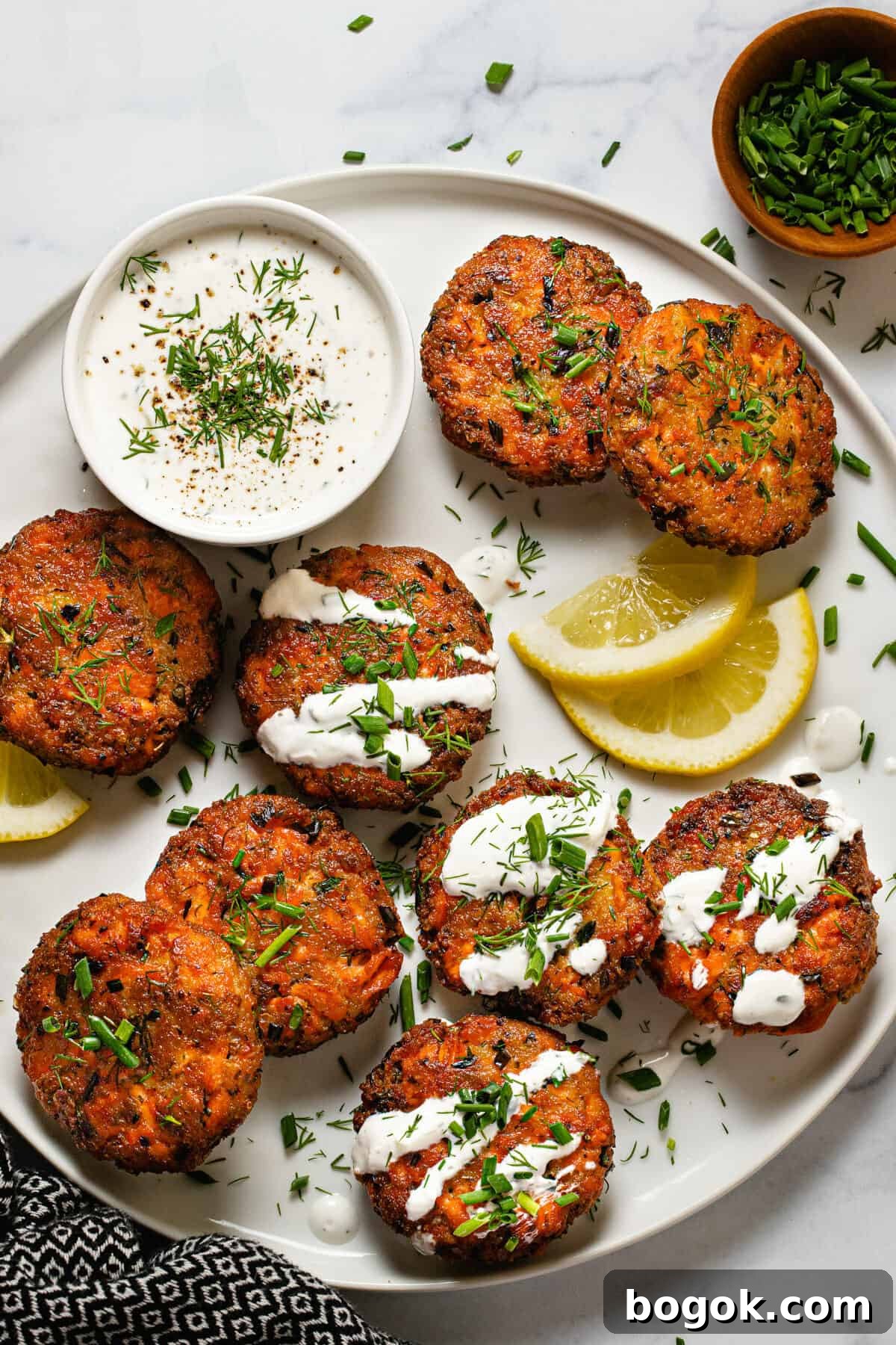 White plate filled with homemade salmon cakes garnished with fresh dill