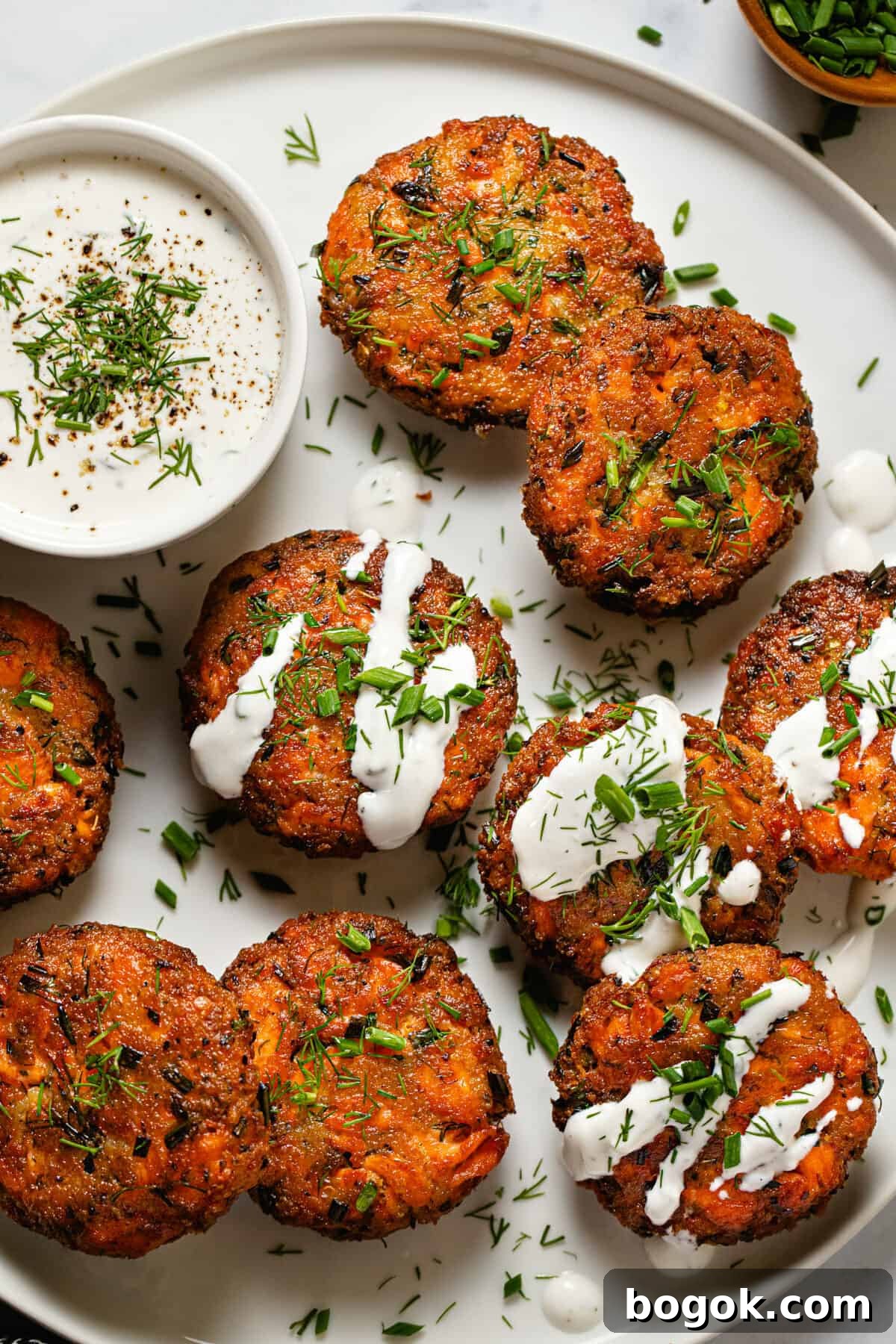 White plate filled with homemade salmon cakes garnished with fresh dill