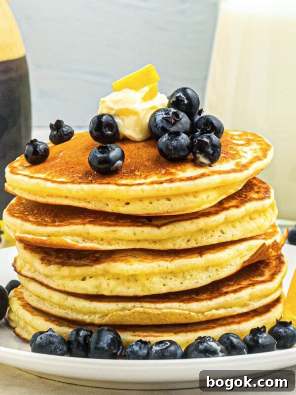 Banana Bread Muffins with Cinnamon Streusel 11 Golden fluffy pancakes stacked on a white plate, topped with blueberries and butter.