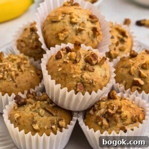 Banana Bread Muffins with Cinnamon Streusel 15 Light golden brown banana bread muffins in white liners, topped with chopped pecans.