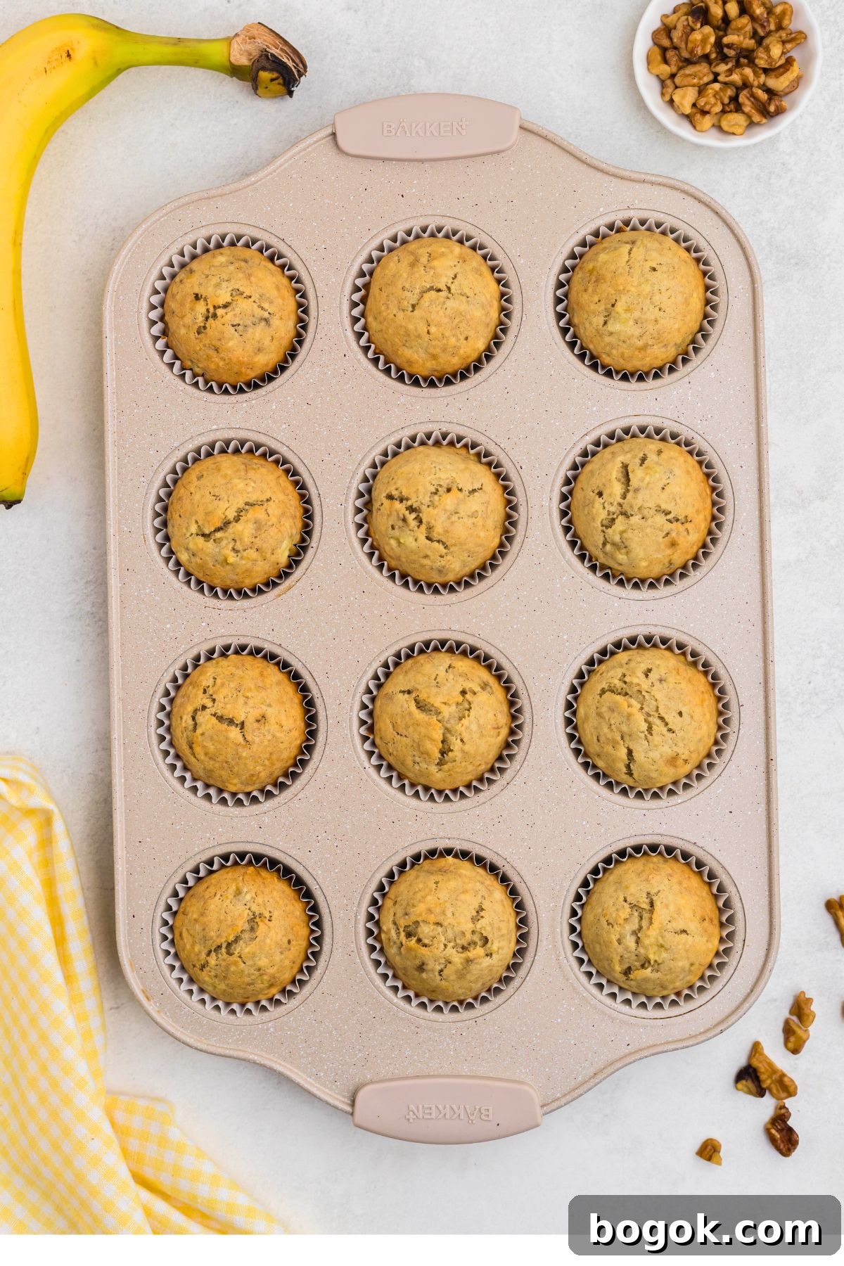 Banana Bread Muffins with Cinnamon Streusel 8 Baked muffins in a muffin pan on a marble table.