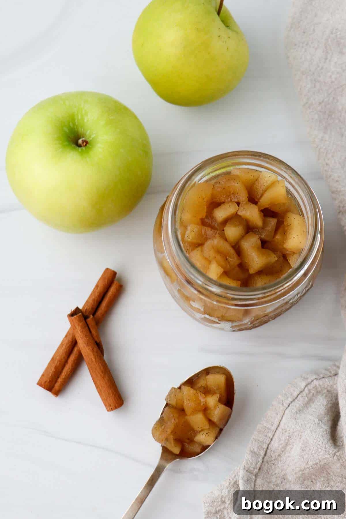 Homemade Apple Compote Recipe 2 Overhead shot of apple compote with cinnamon sticks and apples.