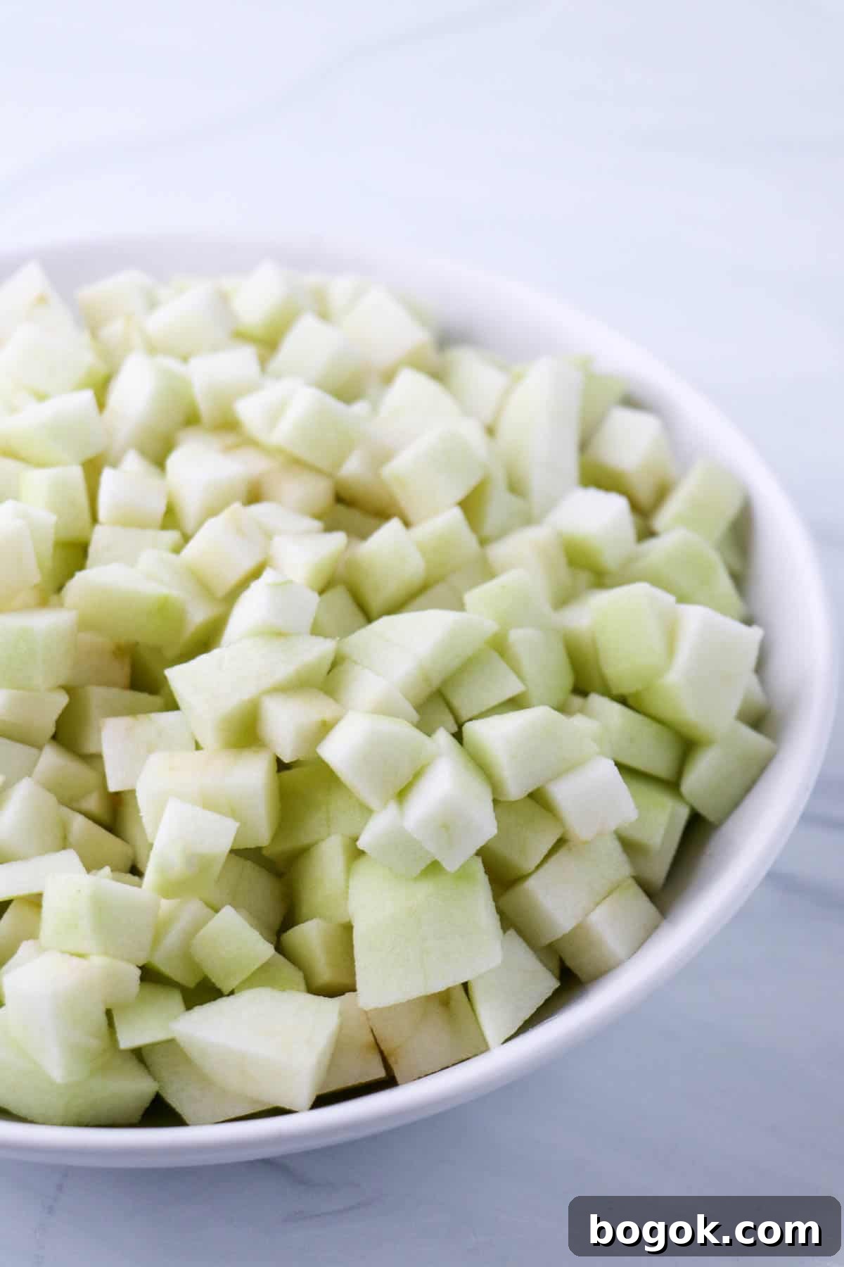Homemade Apple Compote Recipe 4 Chopped up apples in a white bowl.