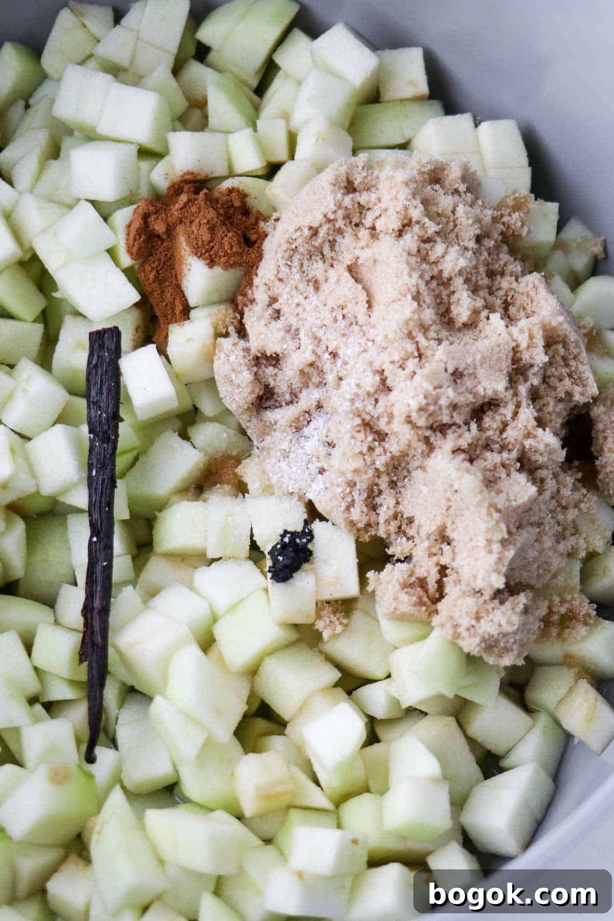 Homemade Apple Compote Recipe 5 Chopped up apples, a vanilla bean, cinnamon and brown sugar in a saucepan.