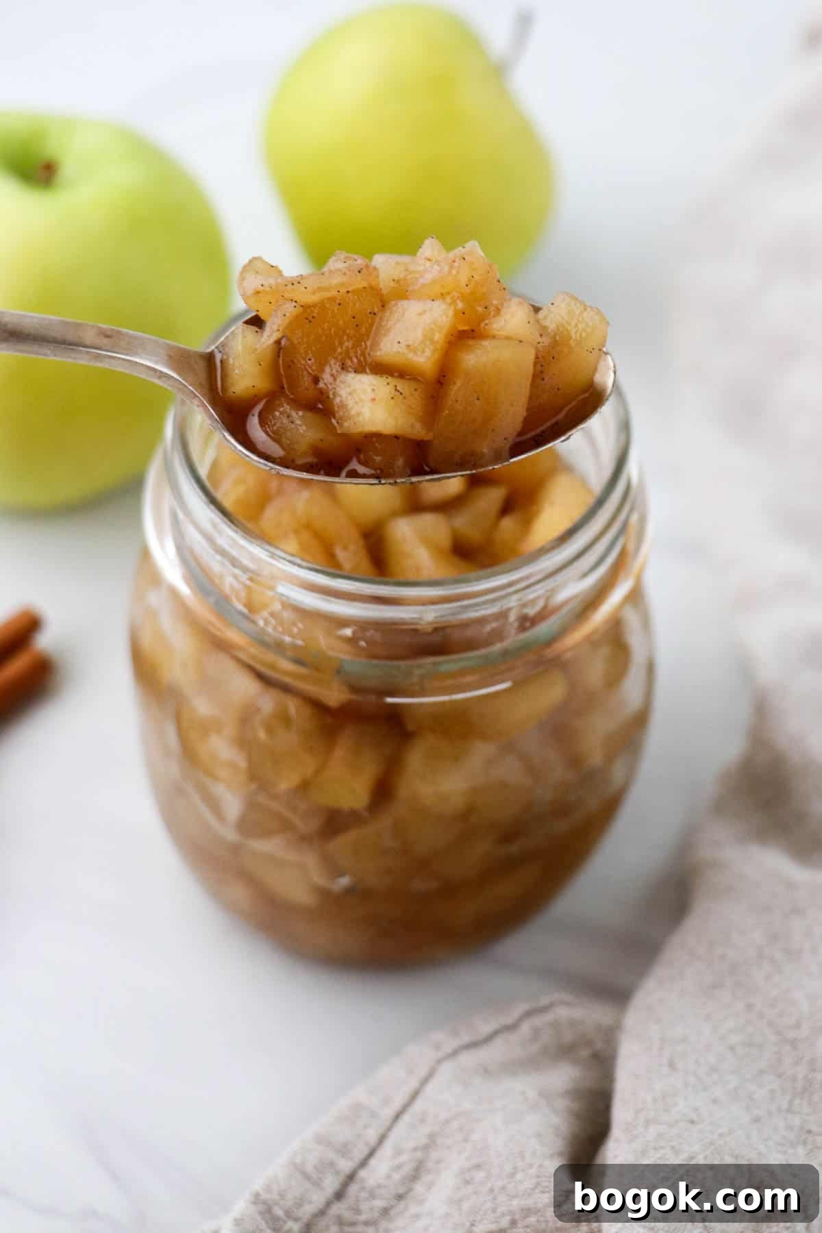 Homemade Apple Compote Recipe 8 Spoonful of apple compote in front of a jar of compote and apples.