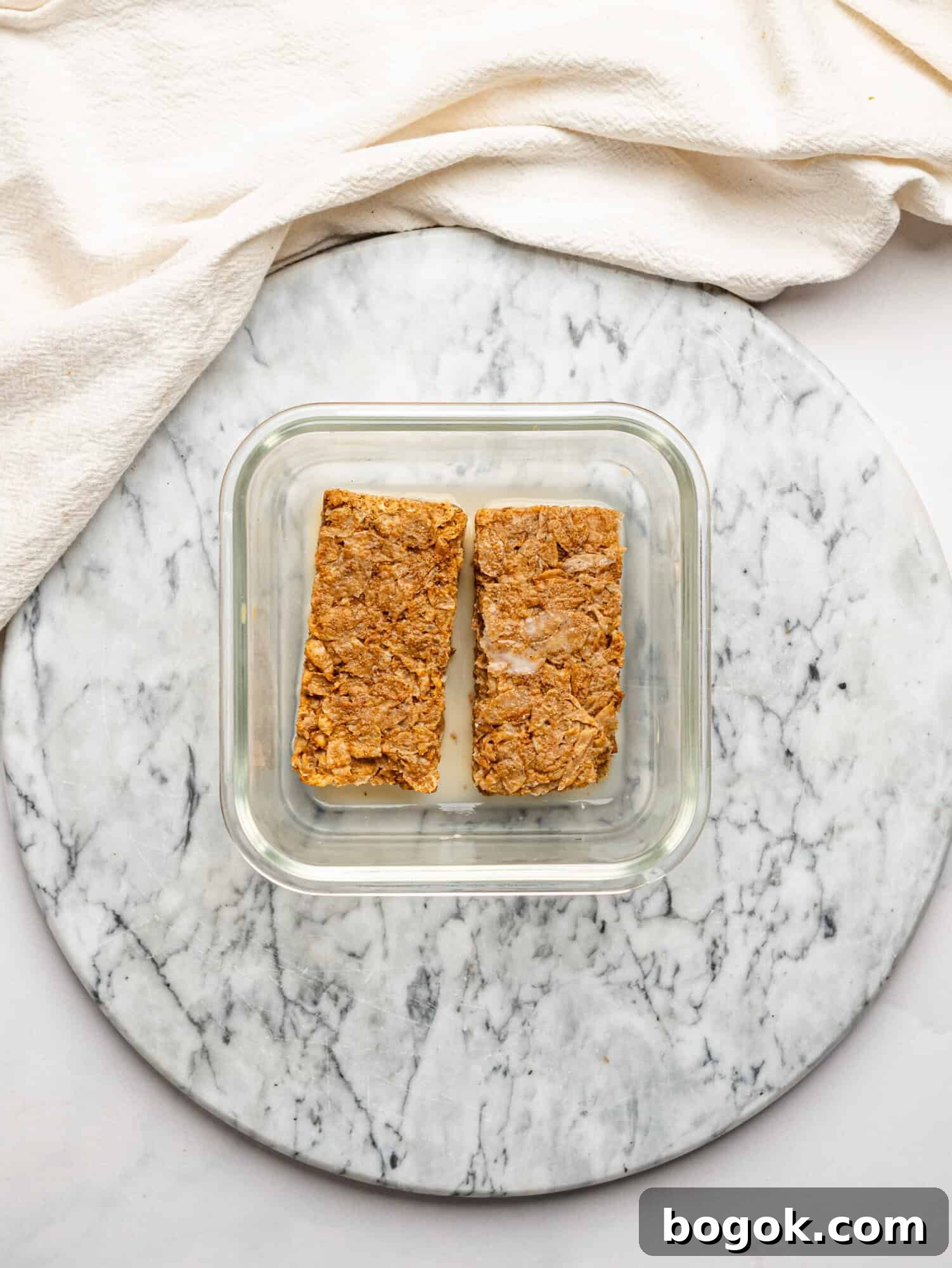 Lemon Cheesecake Overnight Weet-Bix Recipe 7 Weet-Bix biscuits and milk in a glass meal-prep container, ready to form the base of this Lemon Cheesecake Ovenight Weet-Bix.