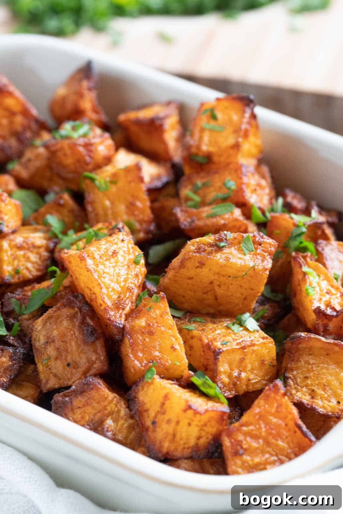 Roasted swede in a serving dish garnished with chopped parsley.