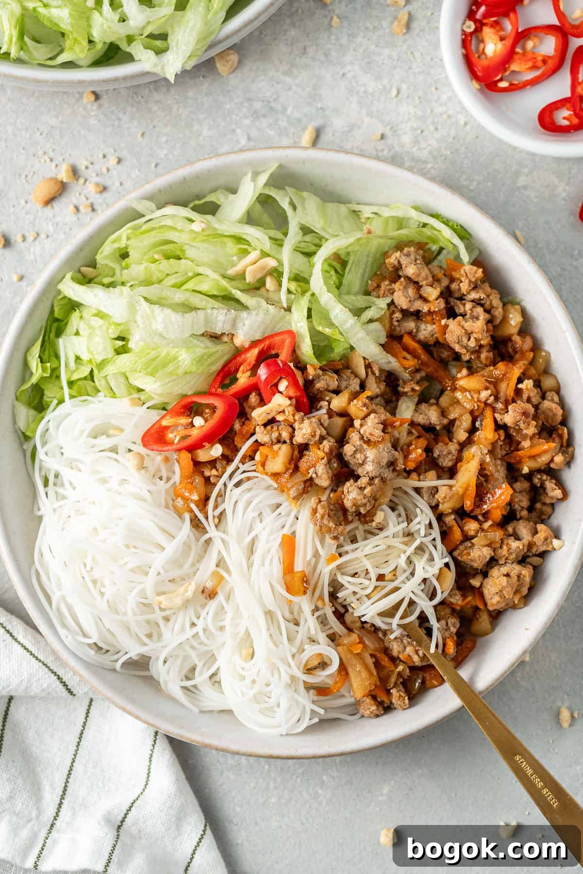 San Choy Bow Lettuce Wrap Bowls - Chinese Pork Recipe 11 A fork tangled up in the noodles in a bowl.