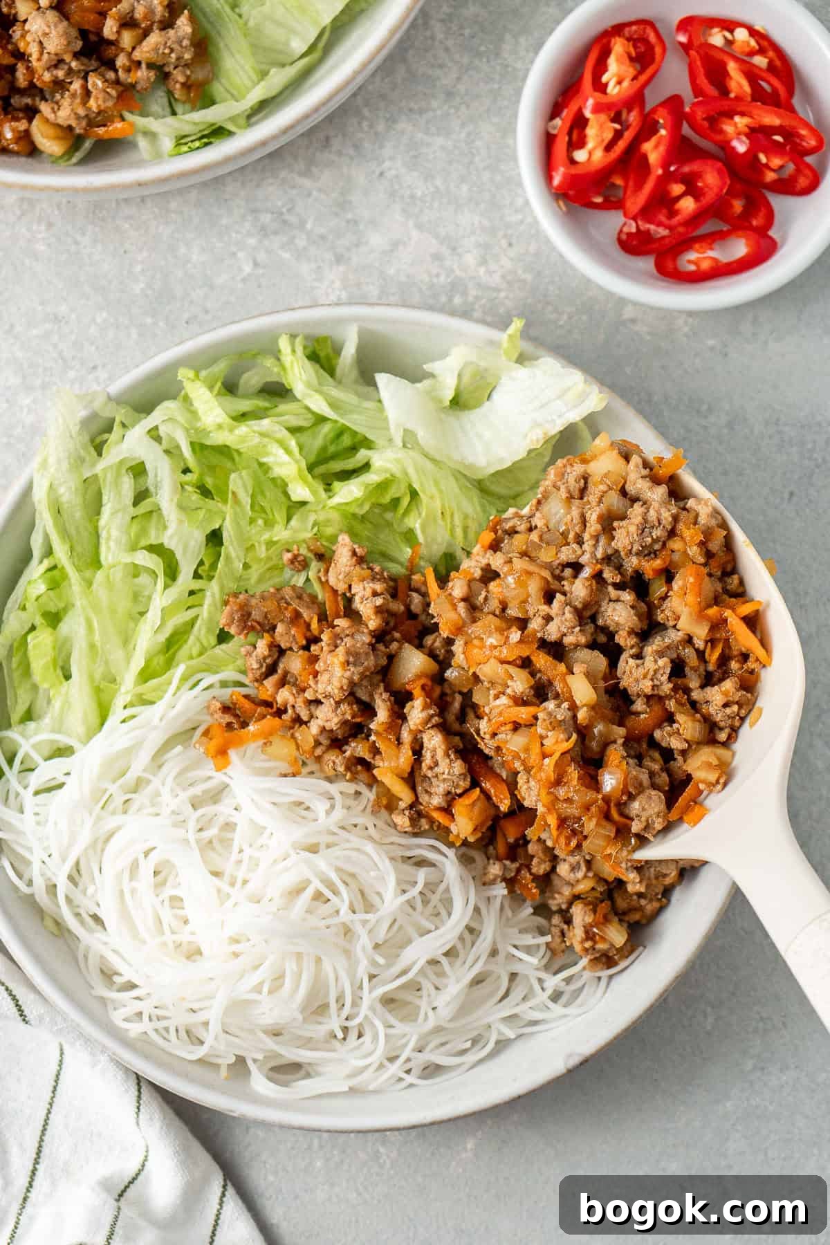San Choy Bow Lettuce Wrap Bowls - Chinese Pork Recipe 9 Spooning the pork mixture over the noodles and lettuce.
