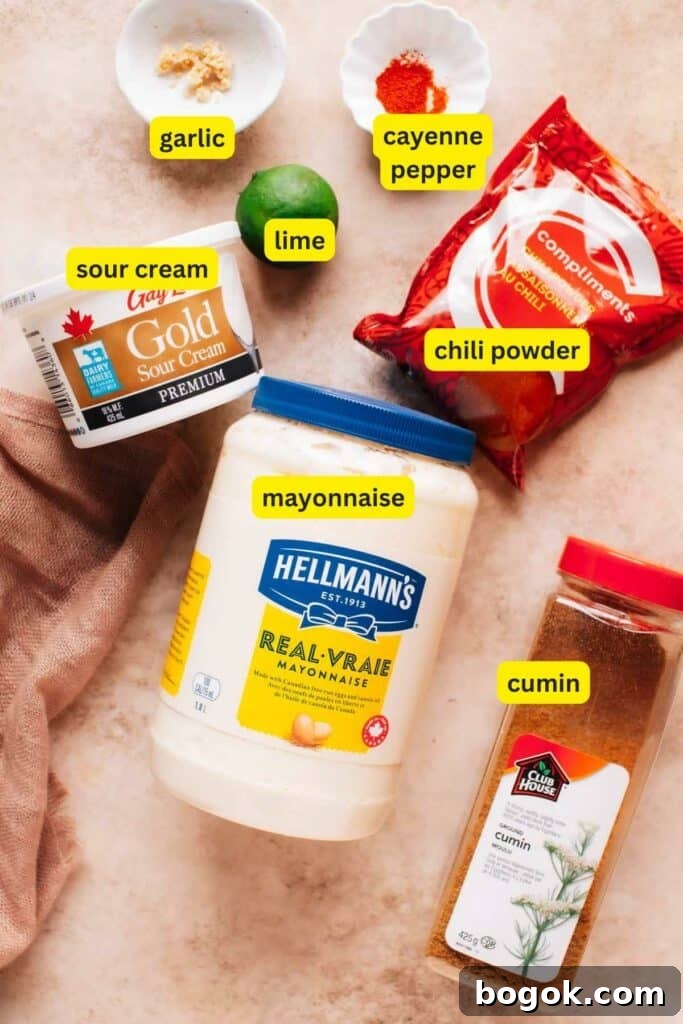 Homemade Creamy Baja Sauce for Fish Tacos 4 Ingredients for Baja sauce are laid out on the kitchen countertop, including mayonnaise, garlic, sour cream, lime, chili powder, cumin, and cayenne pepper.