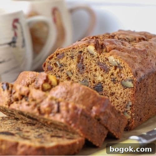 Sourdough date and walnut loaf cake sliced open to show nuts and dates inside the loaf.