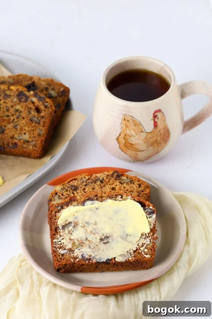 Sourdough date and walnut loaf cake slice on a plate with fresh butter.