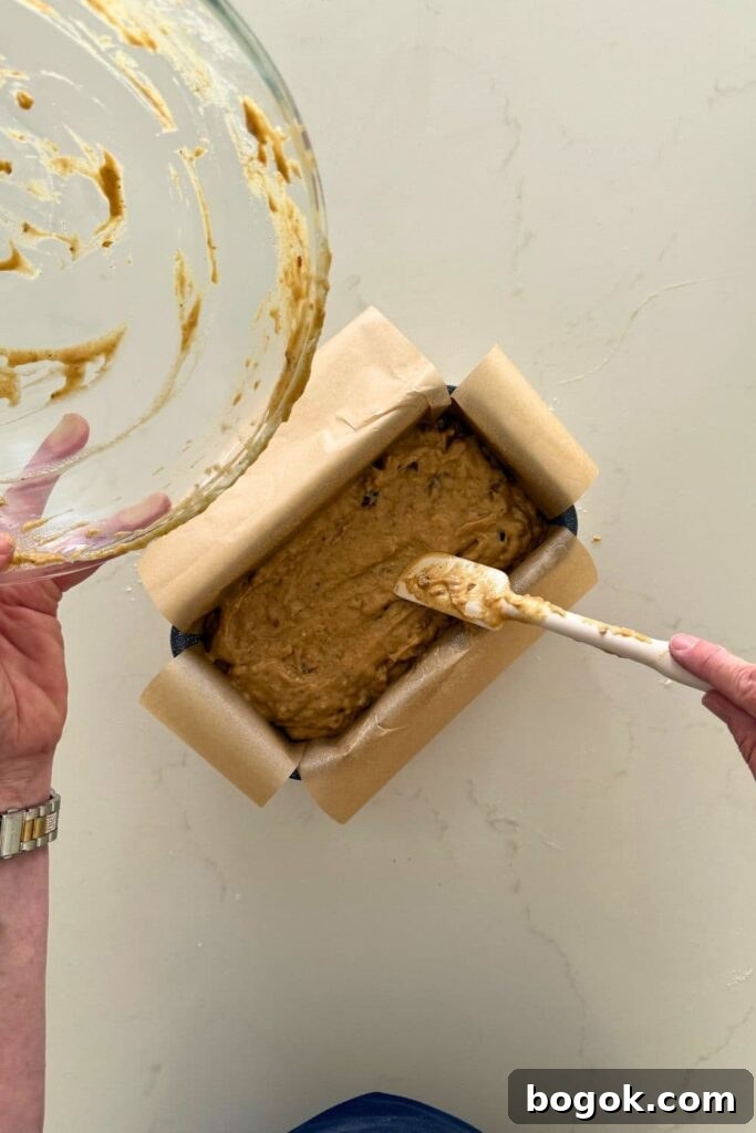 Adding batter to loaf pan to make sourdough date and walnut loaf cake.