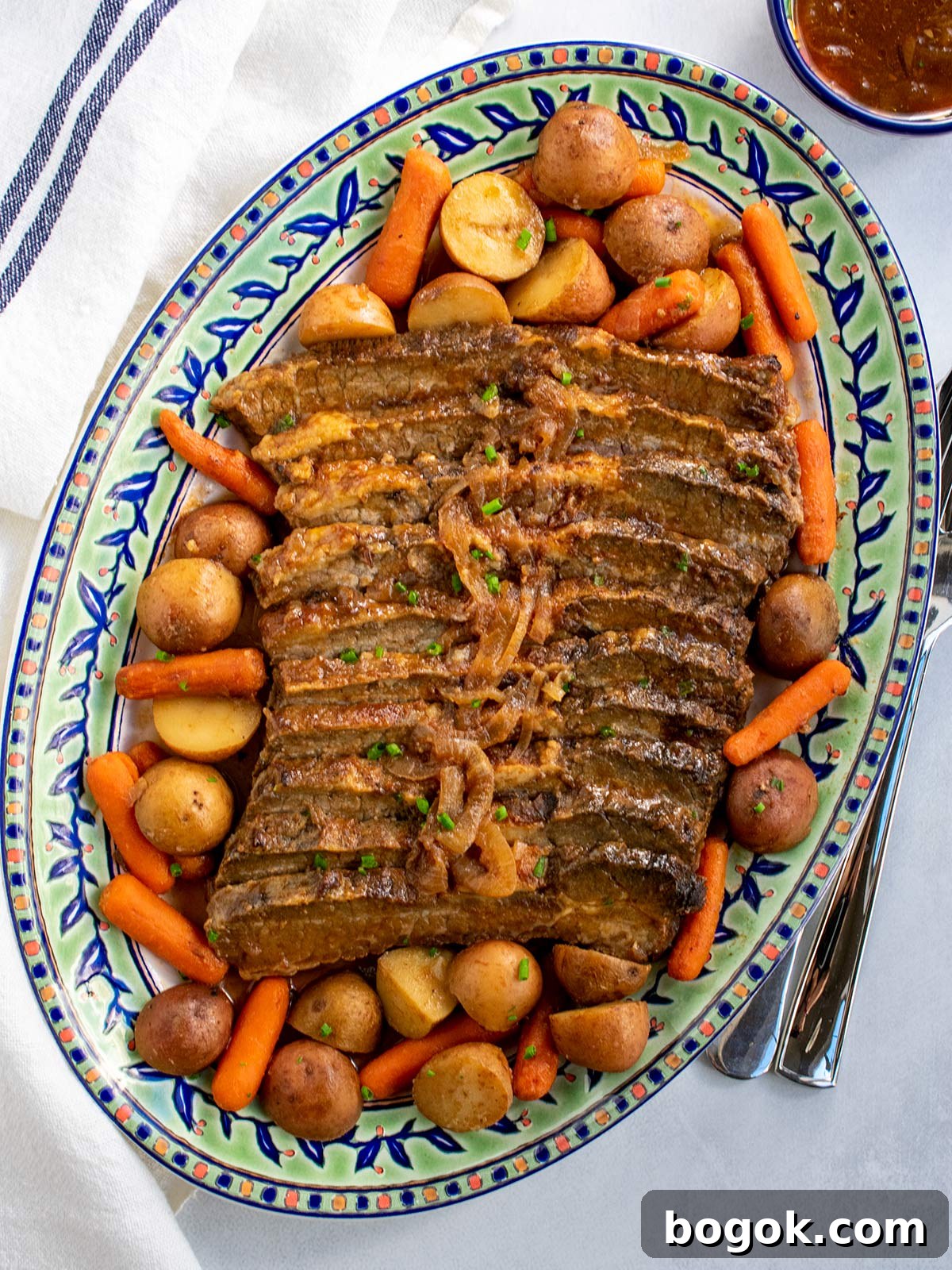 Last-Minute Rosh Hashanah Prep Guide 3 A platter of brisket with potatoes and carrots surrounding the meat and some gravy in a small bowl on the side.