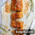 Last-Minute Rosh Hashanah Prep Guide 18 vegetable wellington with 3 slices cut off by a black-handled serrated knife