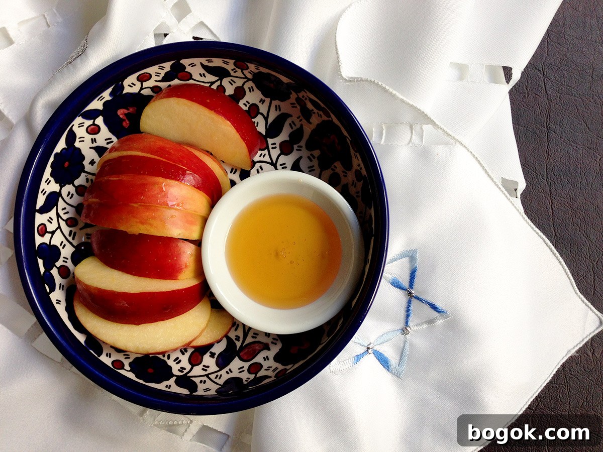 Last-Minute Rosh Hashanah Prep Guide 26 Top down view of a blue bowl with sliced apples and honey in it on a Jewish designed table runner.