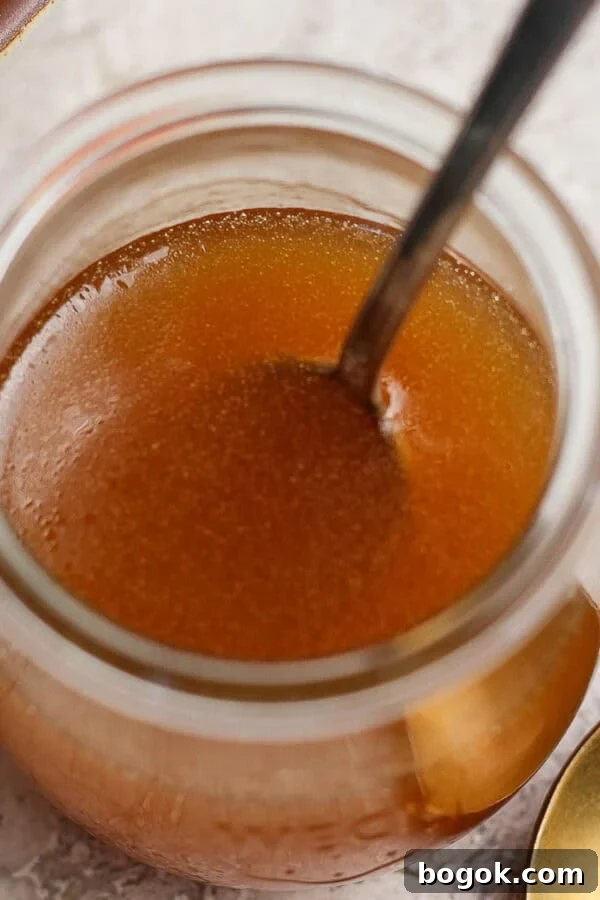 A jar of homemade honey vinaigrette with a spoon sticking out.