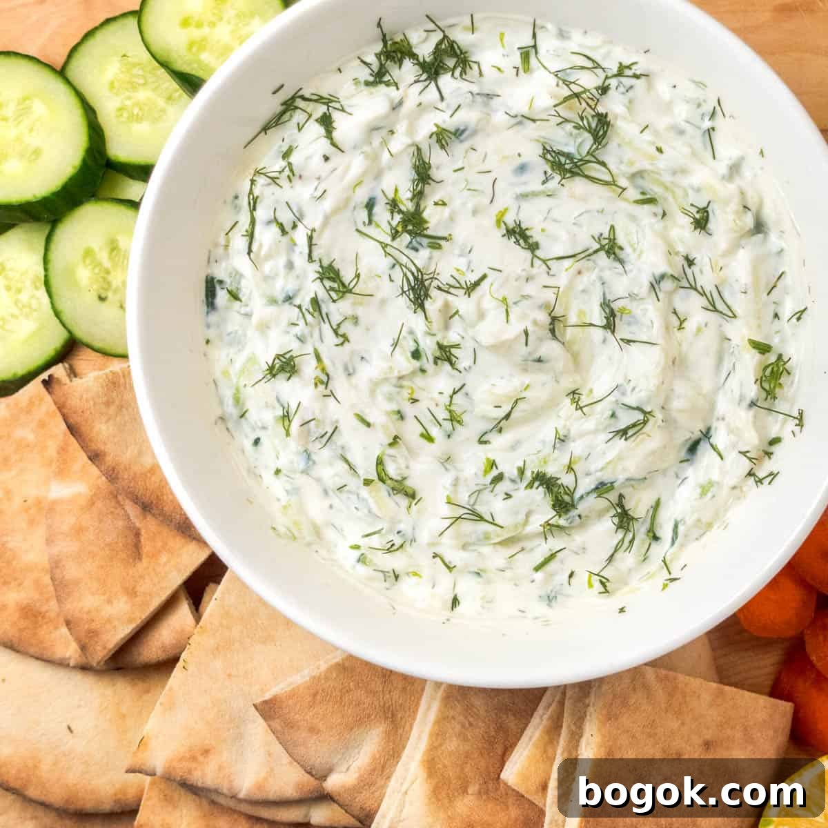 Authentic Greek Tzatziki Sauce Recipe 2 tzatziki sauce in a bowl with and on a platter with vegetables and topped with fresh dill