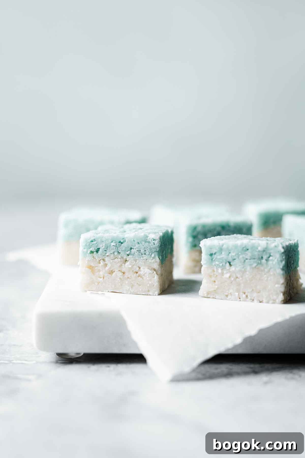 Classic Pink Coconut Ice Candy Recipe 11 Blue and white layered candy squares on a marble tray.