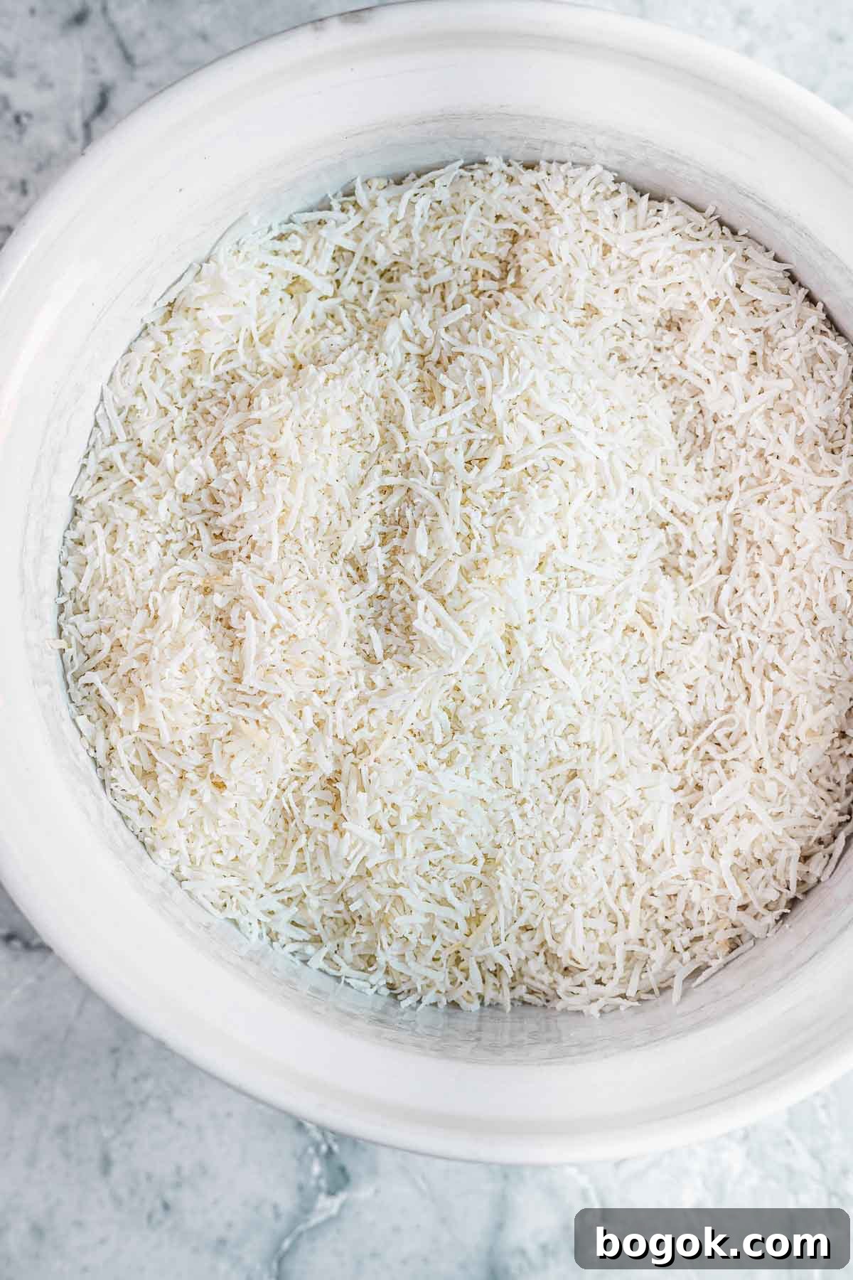 Classic Pink Coconut Ice Candy Recipe 6 Shredded coconut in a white bowl before being chopped fine.