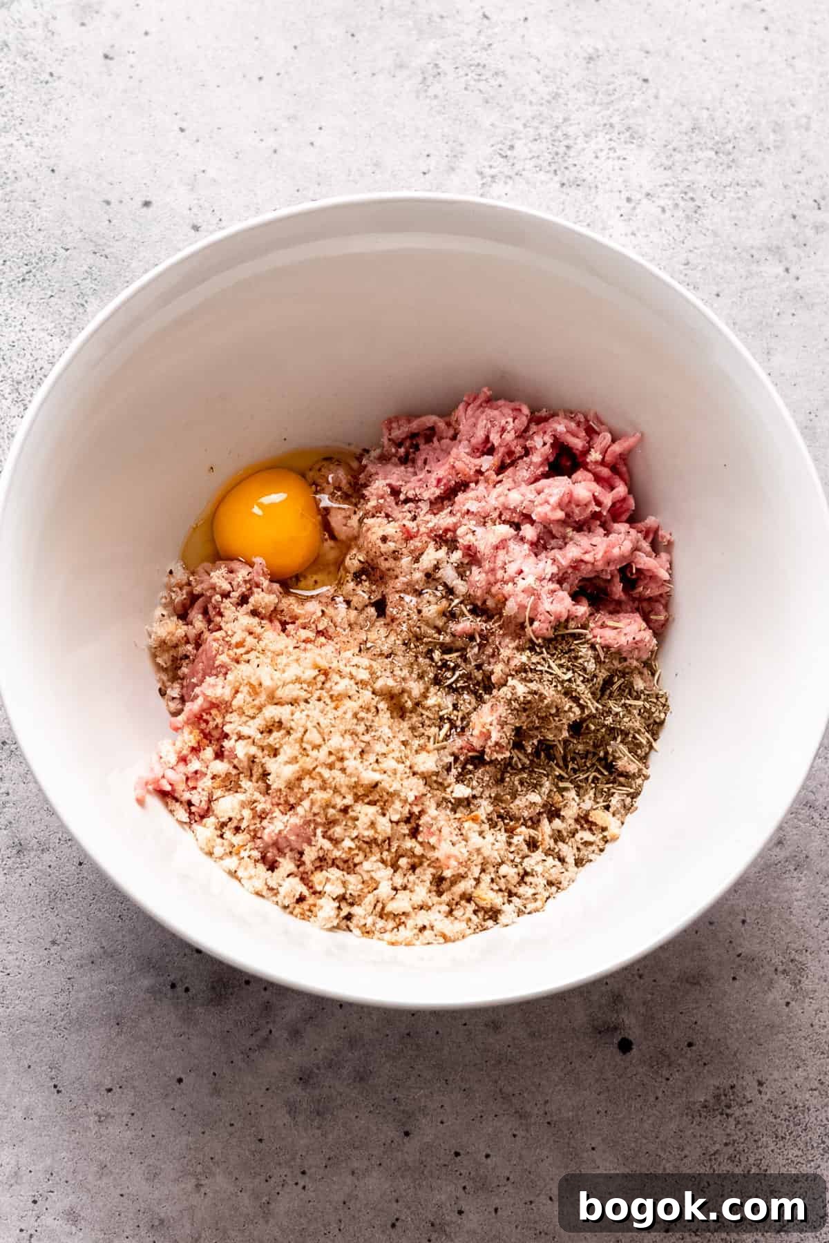 Greek-Style Chicken Meatballs with Lemon & Oregano 3 Greek chicken meatball mixture in a bowl with breadcrumbs and egg.